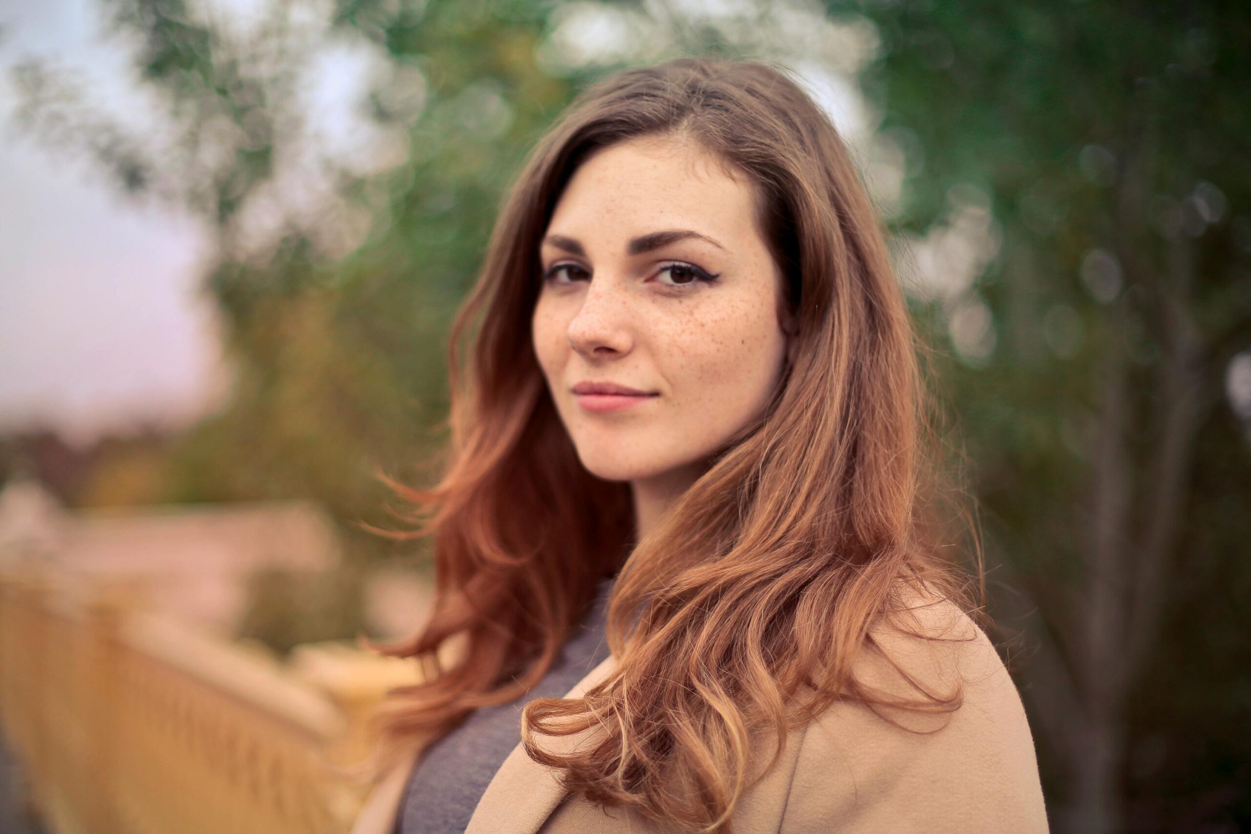 pexels-photo-733872-733872 A young woman with long hair smiles confidently for an outdoor portrait session.